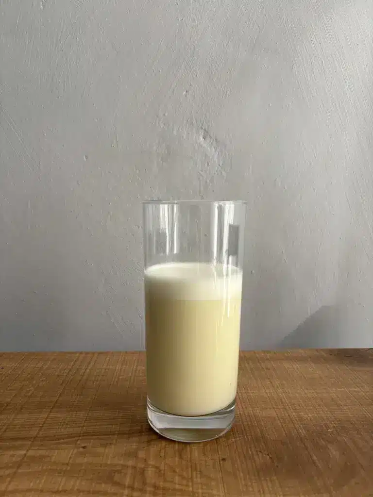 GymBeam Just Whey mit Wasser und einem Shaker zubereitet in einem Glas