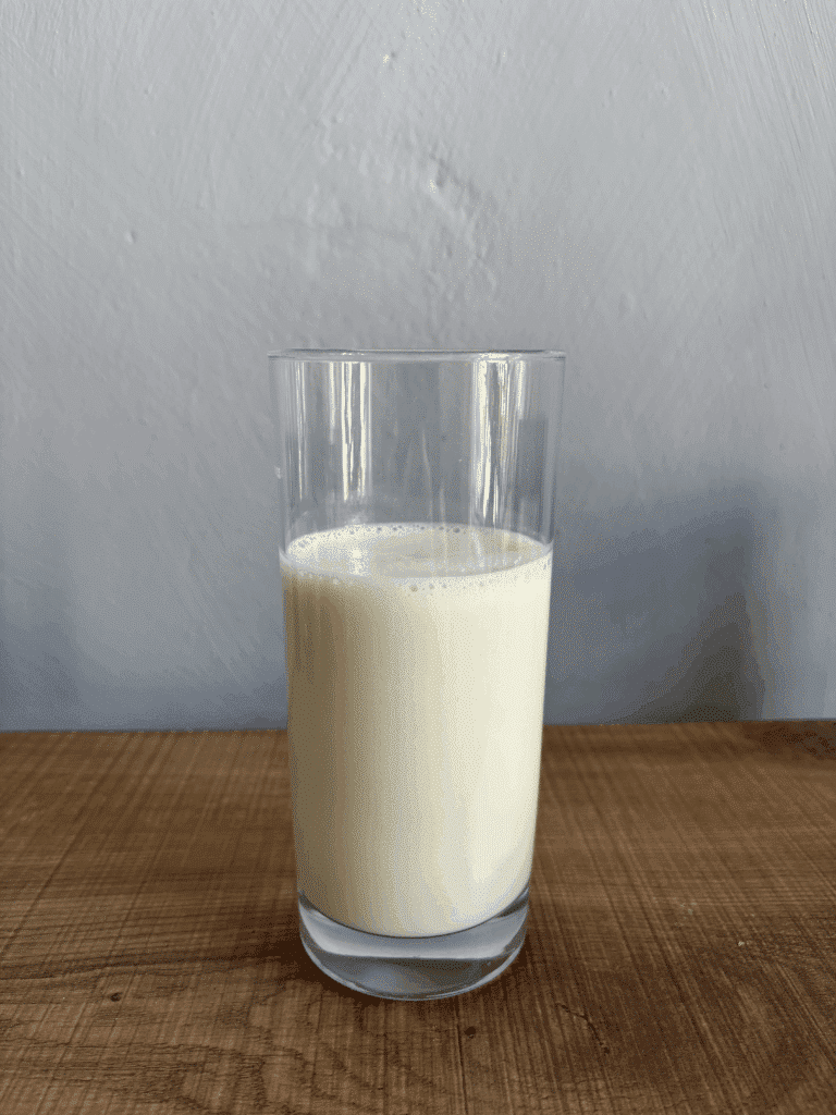 Olimp Whry Protein Complex 100 % mit Vollmilch und einem Shaker zubereitet in einem Glas